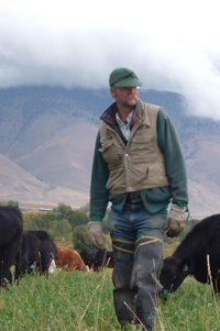 Glenn standing in a field with cows in the background