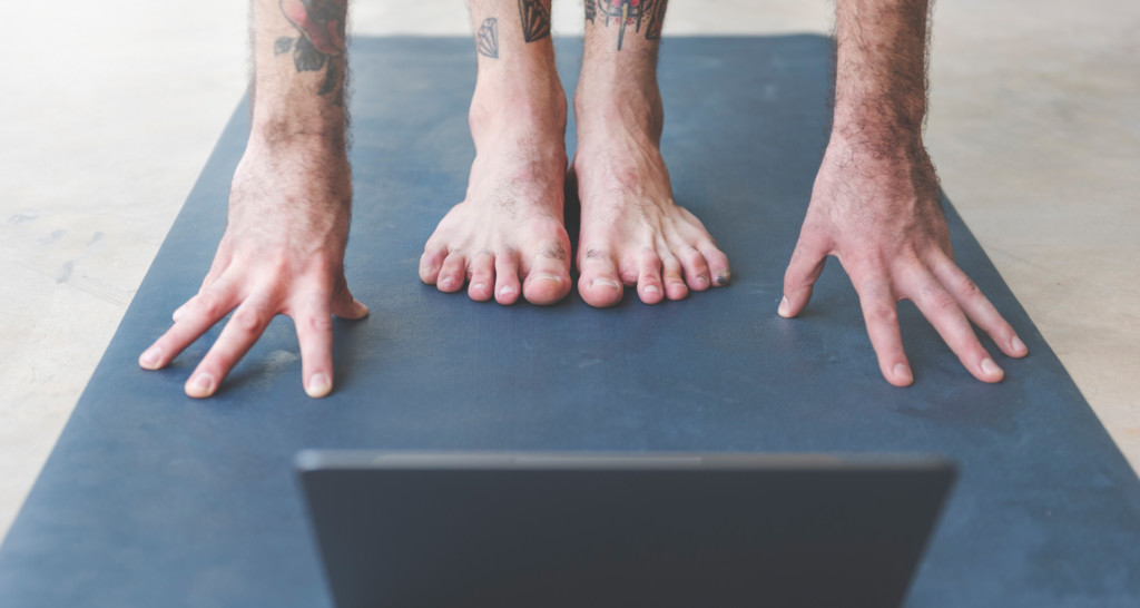 The feet and hands of person doing yoga on mat
