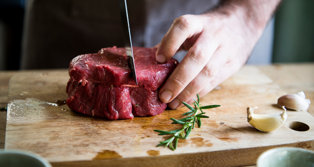 Man cutting into red meat