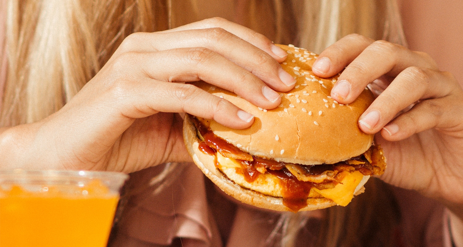 woman eating a bacon cheeseburger that isn't keto-friendly