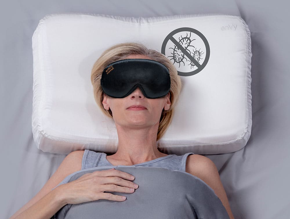 Woman sleeping with an enVy brand Sleep mask and pillow case on her pillow