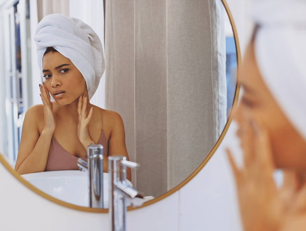 Woman looking at her complexion in mirror after a shower