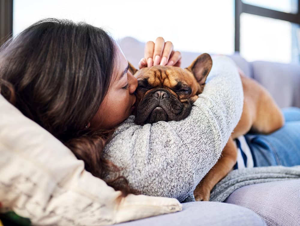Woman snuggling and kissing her adorable dog