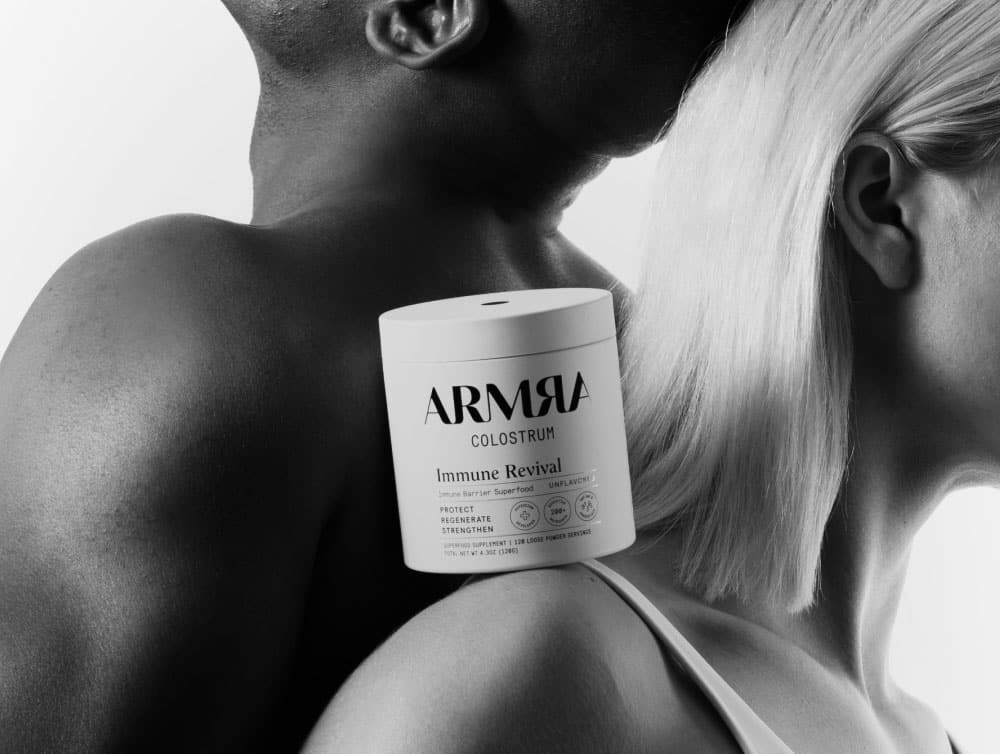 Armra colostrum powder container on the shoulders of a man and woman