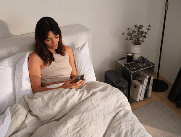 Woman looking at her phone while sitting in bed