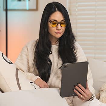 Woman wearing TrueDark Daylights glasses while looking at a tablet