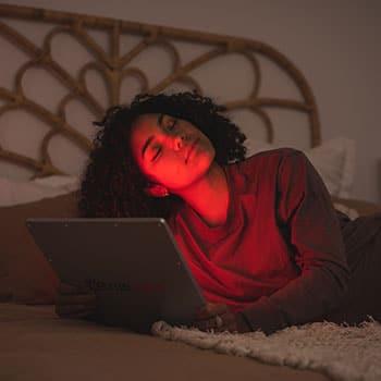 Woman using TrueLight Energy Square 2.4 on her face for red light therapy