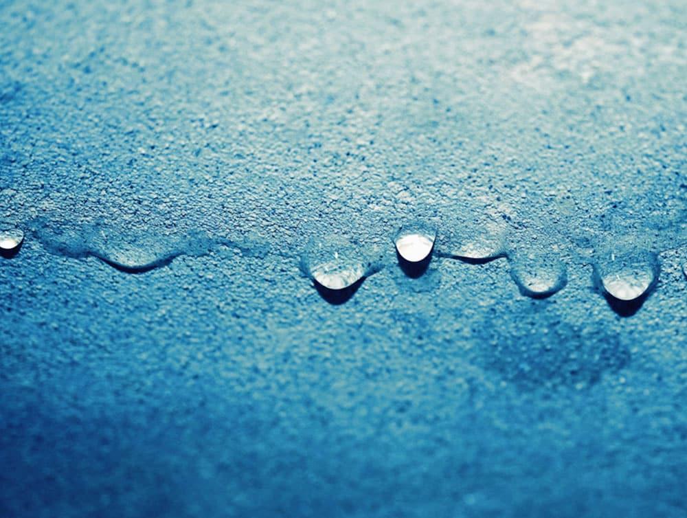 Water droplets collecting on blue surface
