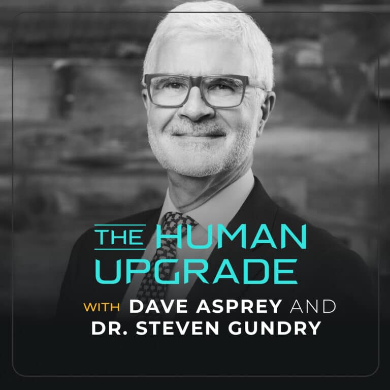 Black and white image of a smiling, grey-haired man in a suit and glasses. Text: The Human Upgrade with Dave Asprey and Dr. Steven Gundry—exploring gut health for a better you.