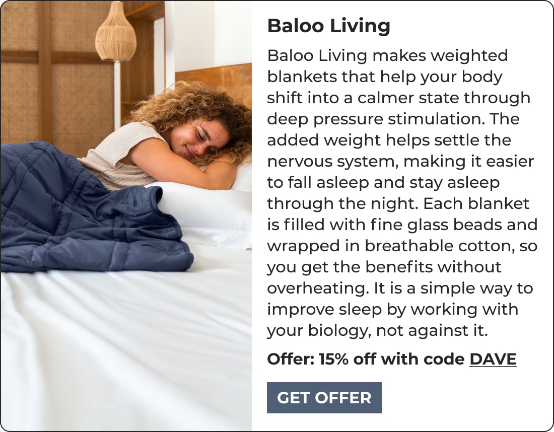 A woman with curly hair smiles while lying on a bed under a dark weighted blanket. Text beside her promotes Baloo Living weighted blankets, renowned biohacking products, offering 15% off with code DAVE.