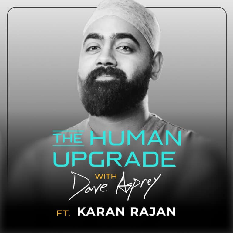 A bearded man in medical scrubs poses confidently. Text reads: The Human Upgrade with Dave Asprey ft. Karan Rajan on a gray gradient background.