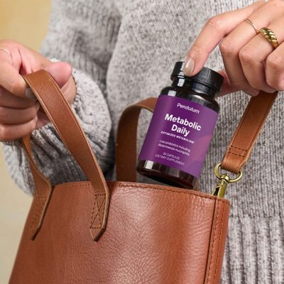 Person placing bottle of Pendulum GLP-1 daily supplement for metabolism in their bag
