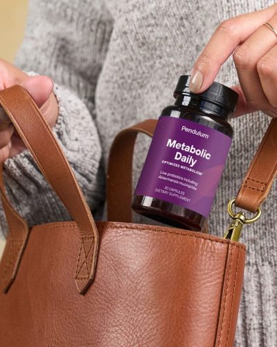 Person placing bottle of Pendulum GLP-1 daily supplement for metabolism in their bag