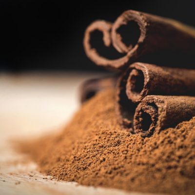 Cinnamon sticks with cinnamon powder on wooden background,