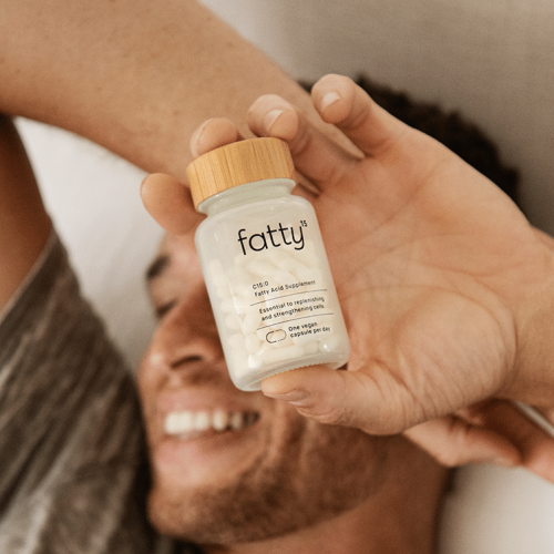 Man holding a bottle of Fatty™ supplements