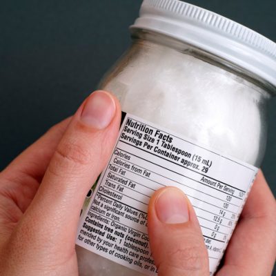 Reading a nutrition facts on organic coconut oil jar.