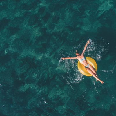 High angle view photo of a young woman relaxing while floating in the ocean using swimming tube; wide photo dimensions