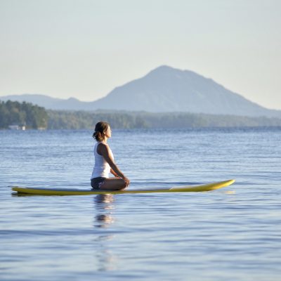 Young Woman doing Yoga on Stand Up Paddle Board, SUP, on Memphremagog Lake in Quebec