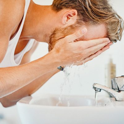 Cropped shot of a young man washing his face in the bathroom
